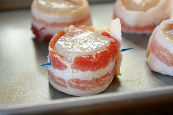 bacon wrapped scallops on a baking sheet ready for the oven