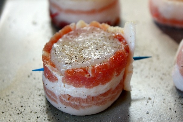 bacon wrapped scallop on a baking sheet ready for the oven