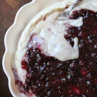 overhead shot of baked brie with blueberry sauce in a scalloped white pie dish