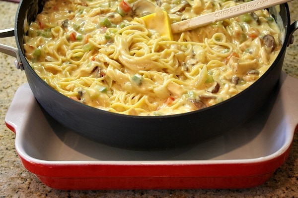 Chicken Spaghetti Casserole recipe from RecipeGirl.com #chicken #spaghetti #casserole #recipe #RecipeGirl making chicken spaghetti casserole in a skillet, ready to pour it into a red and white casserole dish
