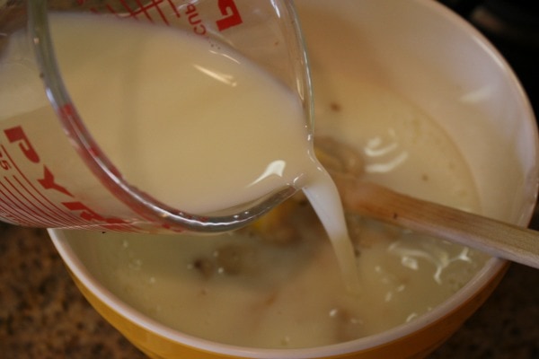 measuring cup pouring into a bowl to make sauce for chicken spaghetti casserole