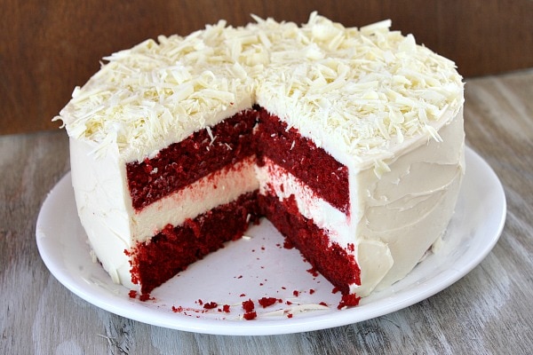 red velvet cheesecake cake sliced open to reveal the inside on a white plate