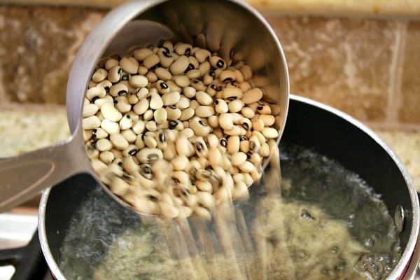 Tex Mex Black Eyed Pea Casserole recipe from RecipeGirl.com #tex #mex #texmex #blackeyedpea #blackeyedpeas #black #eyed #pea #peas #casserole #newyears #newyearsday #lucky #good #luck #goodluck #recipe #RecipeGirl pour peas in a pot of water