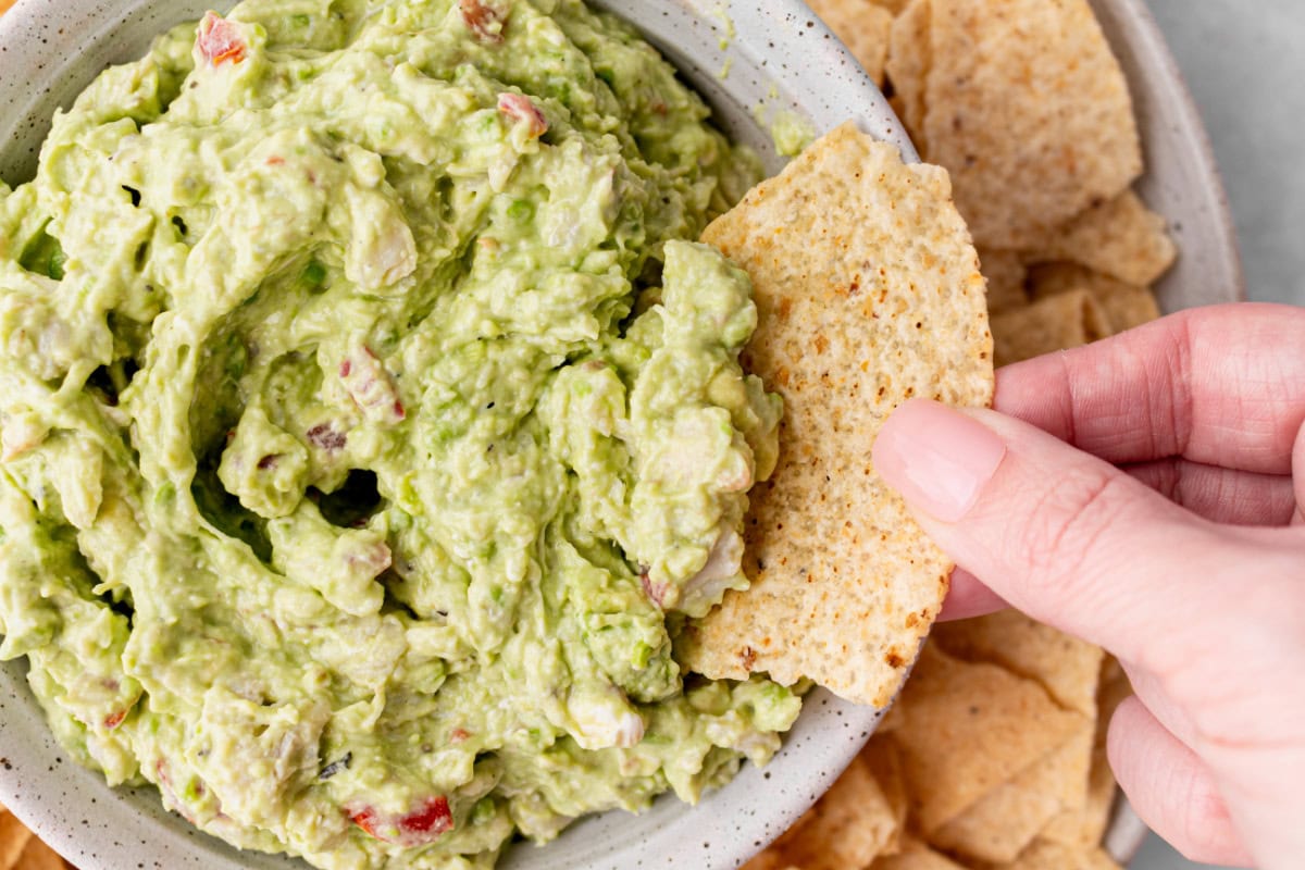 Crab Guacamole is a creamy, fresh twist on classic guacamole with avocado, crab and lime. Easy and perfect for entertaining! chip dipping into bowl of crab guacamole