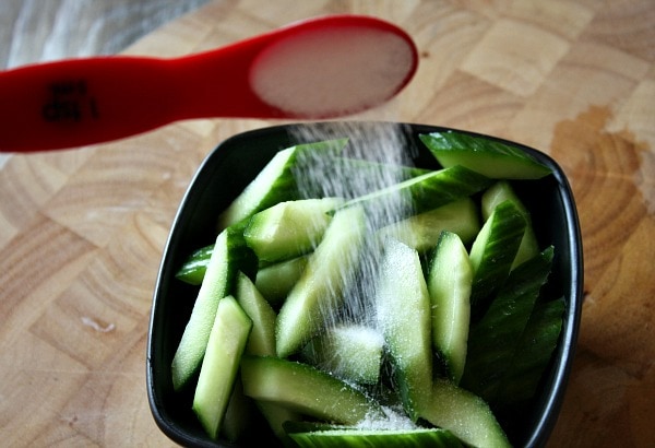 adding salt to cucumbers to make Cucumber Salad