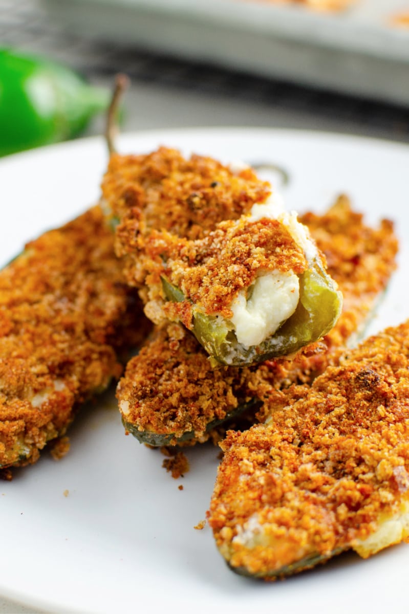 Baked jalapeno poppers stacked on a white plate