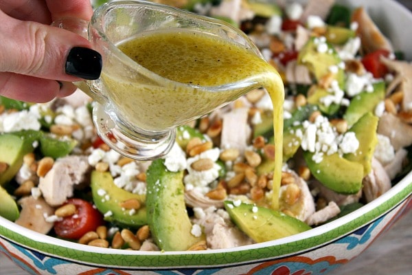 Spinach Salad with Chicken, Avocado and Goat Cheese recipe from RecipeGirl.com #spinach #salad #chicken #avocado #goat #cheese #goatcheese #recipe #RecipeGirl Pouring dressing onto Spinach Salad with Chicken, Avocado and Goat Cheese