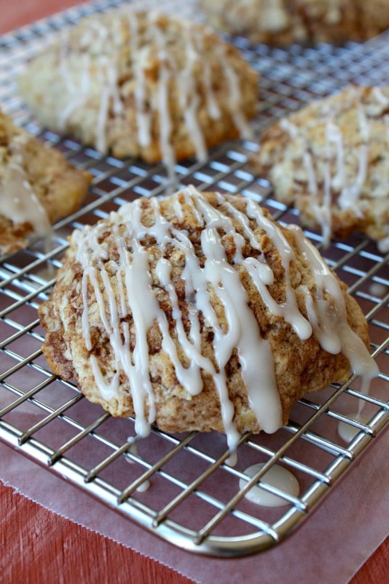 cinnamon bun scones with glaze on a cooling rack