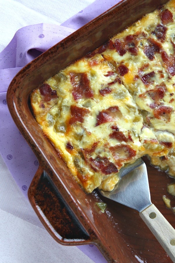 Green Chile and Egg Bake in a brown casserole dish with a spatula