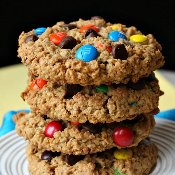 stack of monster cookies on a white plate with a yellow and black background