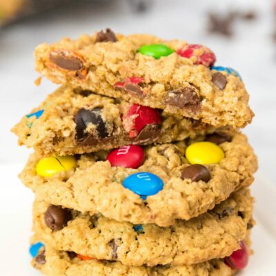 stack of monster cookies with the cookie on top split in half to show the inside