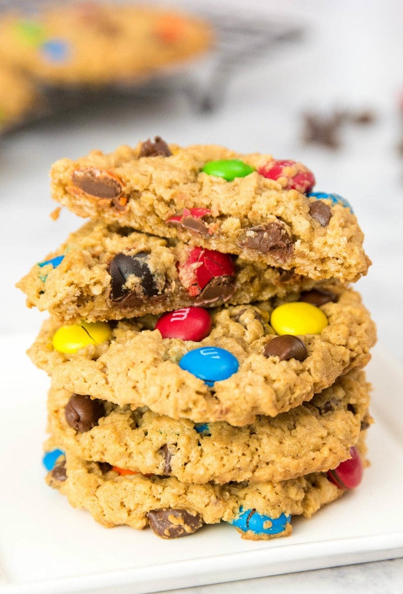 stack of monster cookies with the cookie on top split in half to show the inside