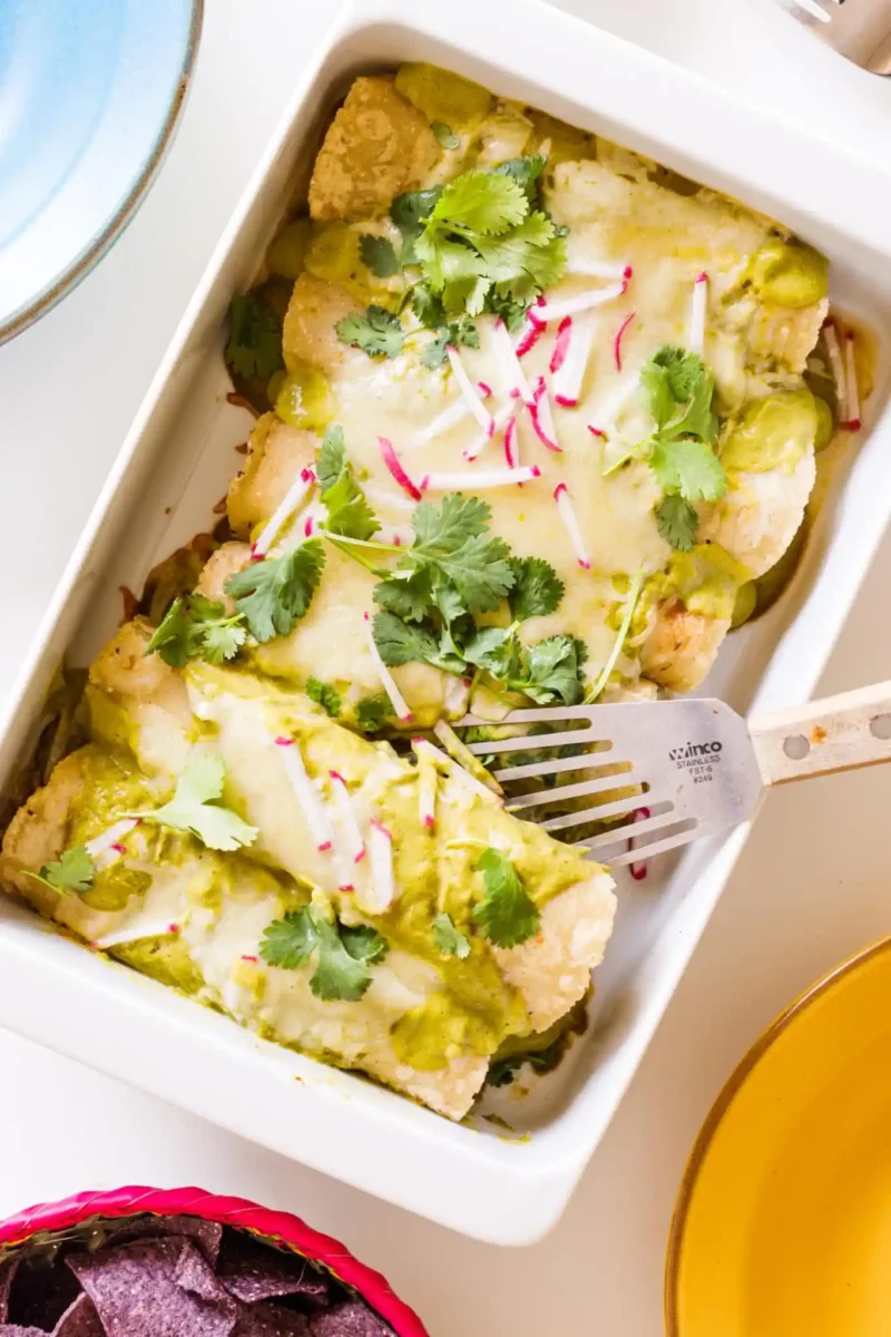 cheesy seafood green enchiladas in a white casserole dish