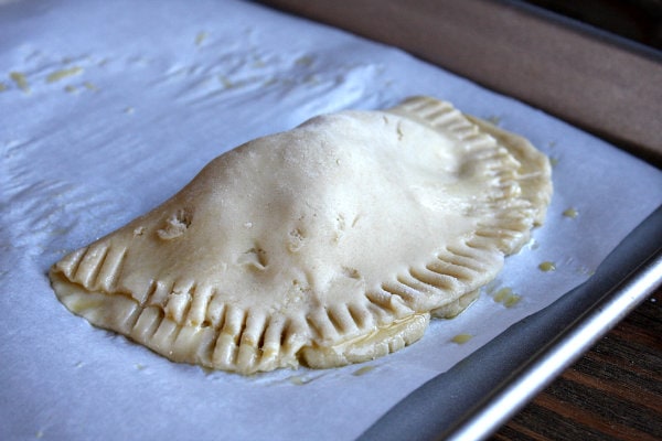 Berry Hand Pie on a baking sheet before baking showing fork sealing on the edges