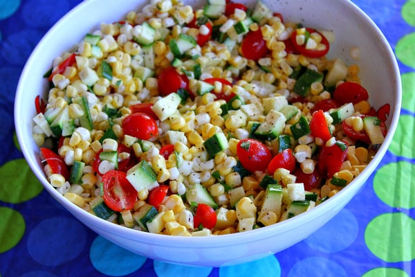 Fresh Corn, Zucchini and Tomato Salad in a white bowl set on a blue and green polka dot tablecloth