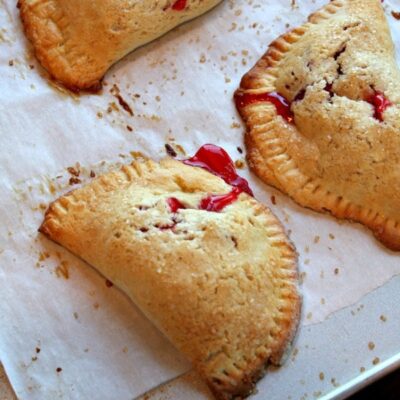 three berry hand pies on a baking sheet lined with parchment paper