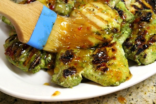 Easy Grilled Cilantro Chicken recipe from RecipeGirl.com #easy #grilled #cilantro #chicken #thighs #recipe #RecipeGirl brushing sauce onto chicken