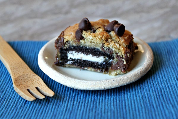 Oreo and Caramel Stuffed Chocolate Chip Cookie Bar on a white plate with a fork set on a blue placemat