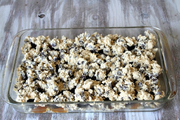 How to Make Oreo and Caramel Stuffed Chocolate Chip Cookie Bars showing cookie dough in the pyrex pan