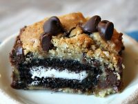 oreo and caramel stuffed chocolate chip cookie bar on a white plate set on a blue placemat