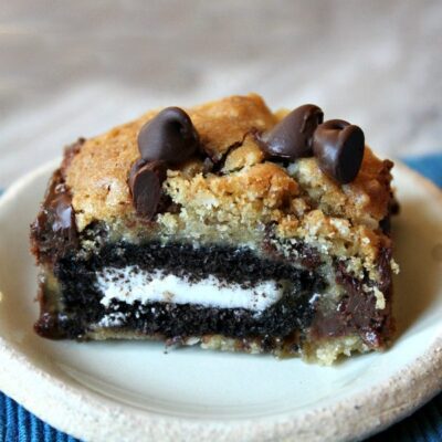 oreo and caramel stuffed chocolate chip cookie bar on a white plate set on a blue placemat