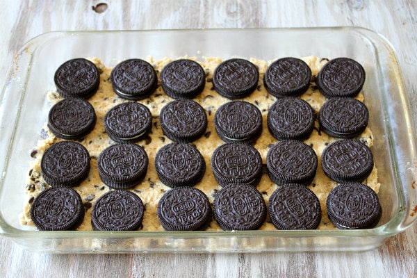 How to Make Oreo and Caramel Stuffed Chocolate Chip Cookie Bars with a layer of cookie dough with oreos on top in a pyrex pan