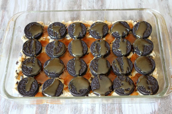 How to Make Oreo and Caramel Stuffed Chocolate Chip Cookie Bars showing a layer of oreos with caramel on top in a pyrex pan