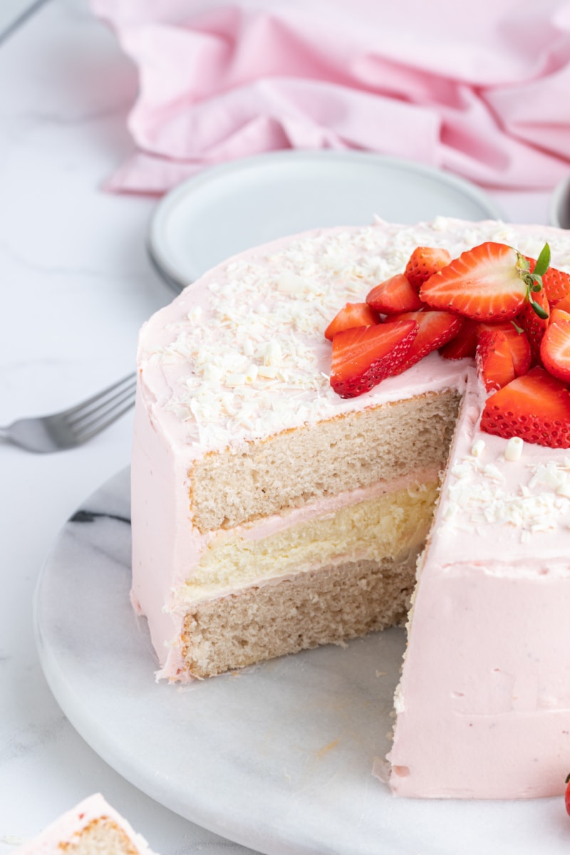 strawberry cheesecake cake with big slice taken out of it