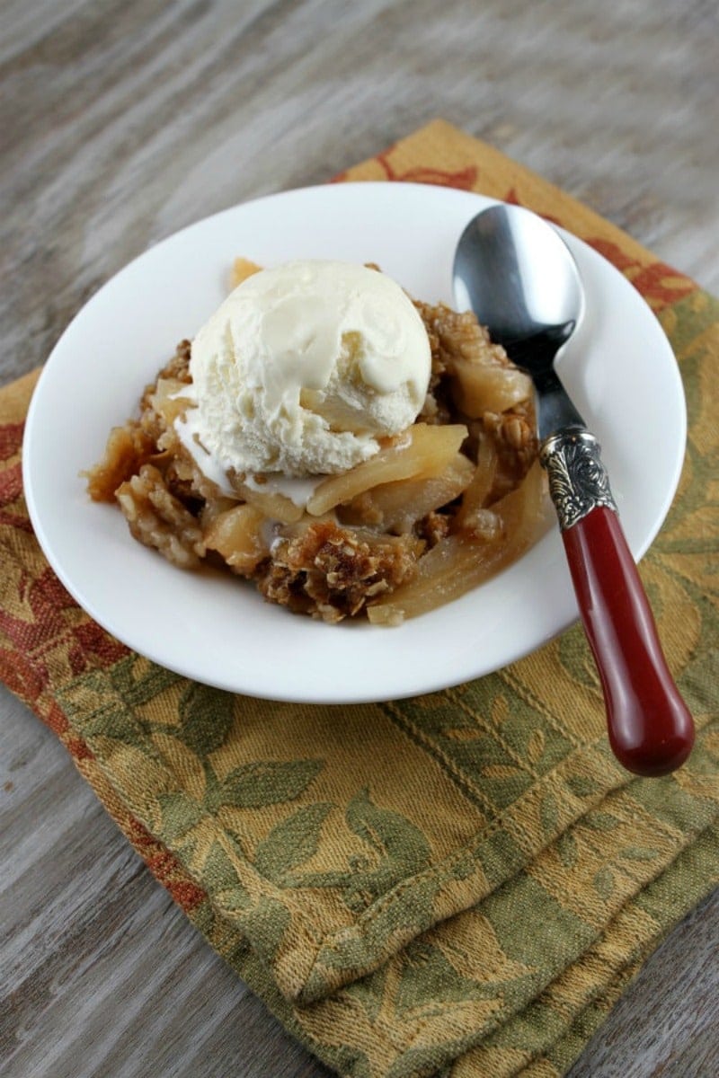 apple crisp topped with ice cream in a white bowl