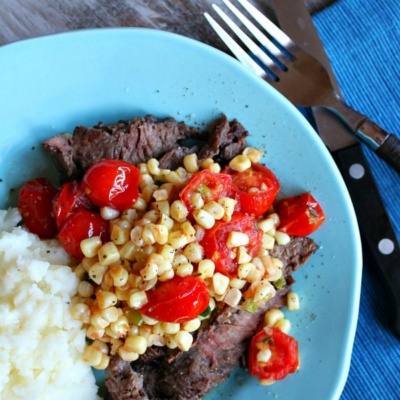 grilled skirt steak with corn and cherry tomato salad on plate