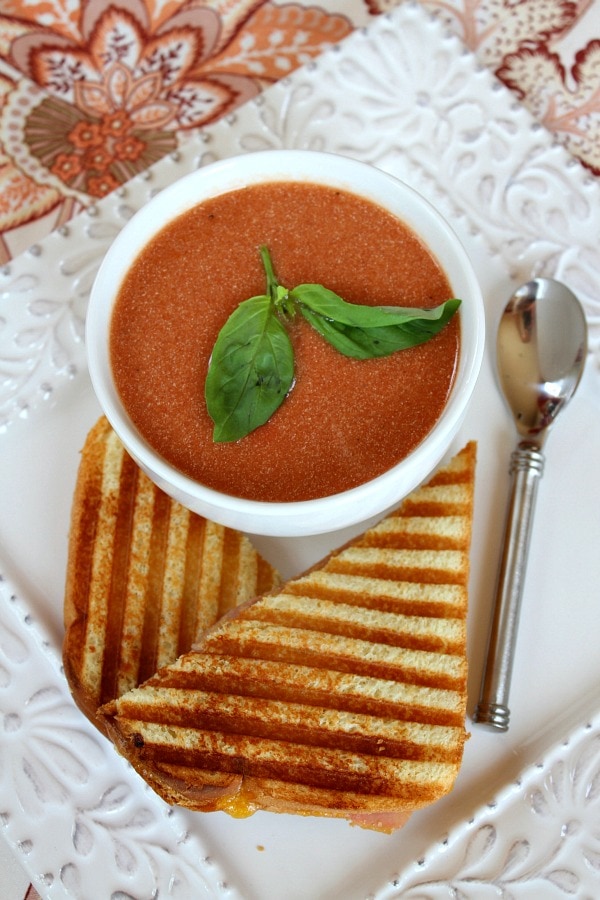 10 Minute Easy Tomato Soup recipe from RecipeGirl.com bowl of tomato soup with fresh basil and a grilled cheese sandwich