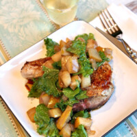 pean seared pork chops with pear on a white plate with glass of wine