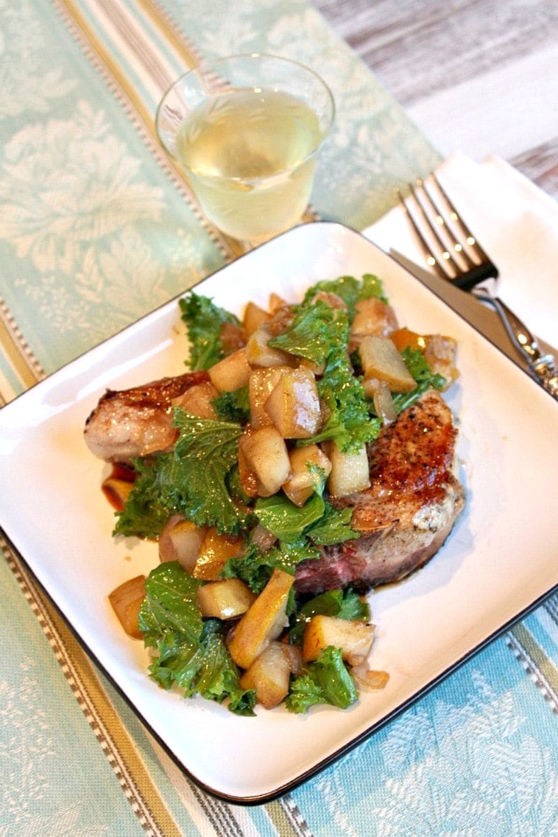 pean seared pork chops with pear on a white plate with glass of wine