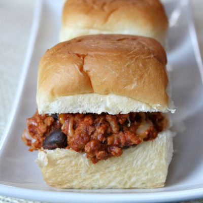 Three sloppy joe sliders lined up on a platter