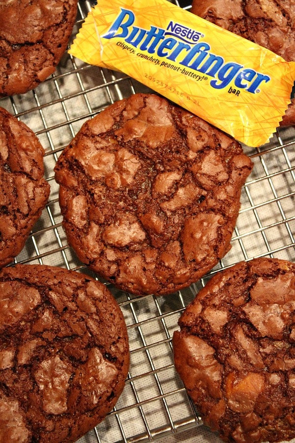 overhead shot of Butterfinger Brownie Cookies on a cooling rack with a wrapped mini Butterfinger bar lying on the rack too