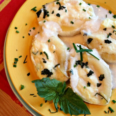 three cheese stuffed shells on a plate with cream sauce
