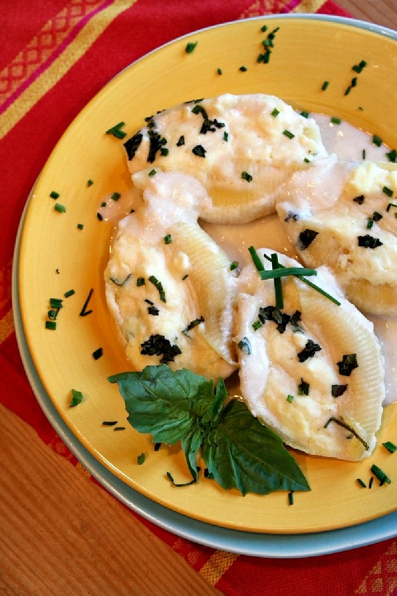 three cheese stuffed shells on a plate with cream sauce
