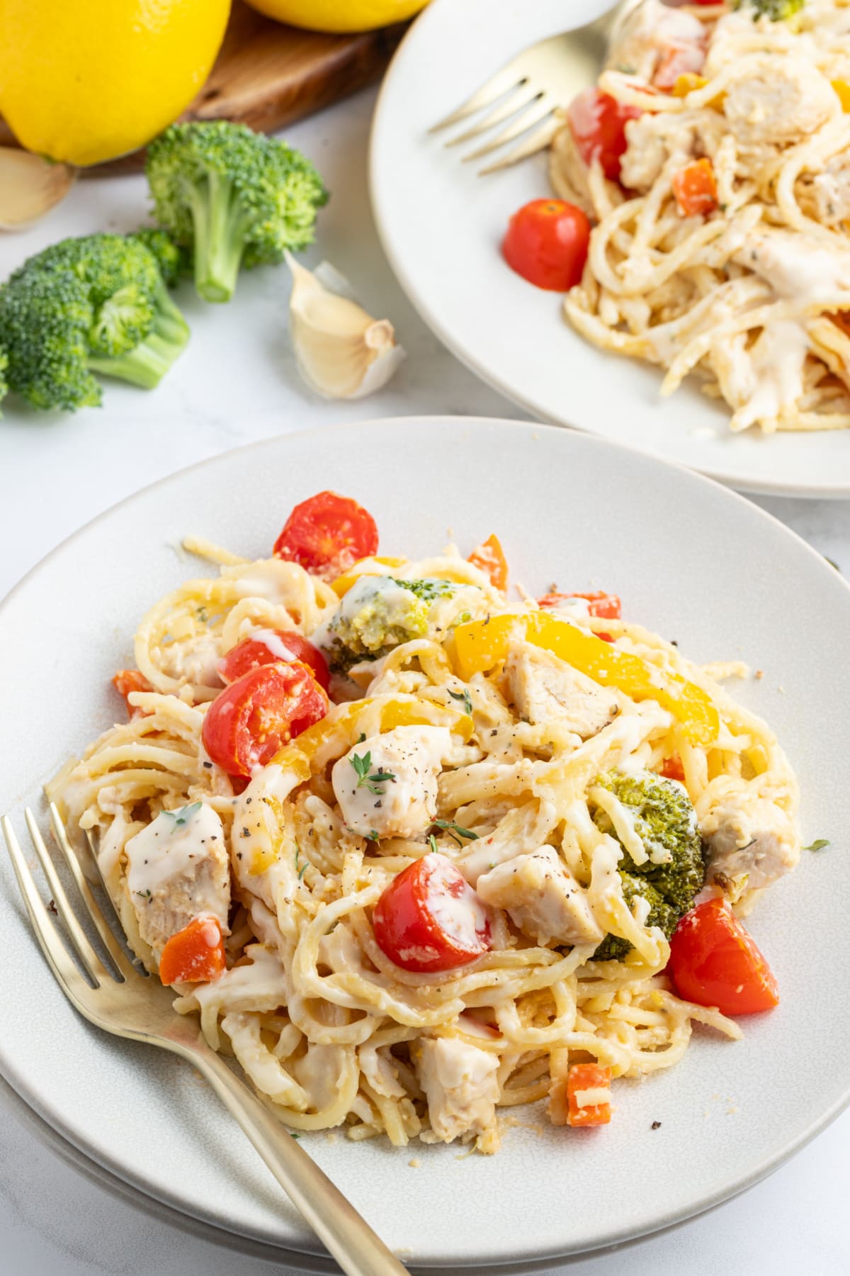 serving of baked lemon chicken spaghetti primavera on a plate with a fork