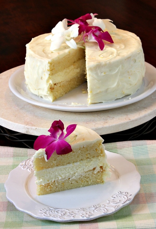 lemon cheesecake cake on plate and slice on plate, garnished with edible flowers