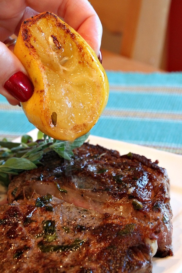 Pan Fried Lemon- Garlic Rib-Eye Steaks with lemon being drizzled on