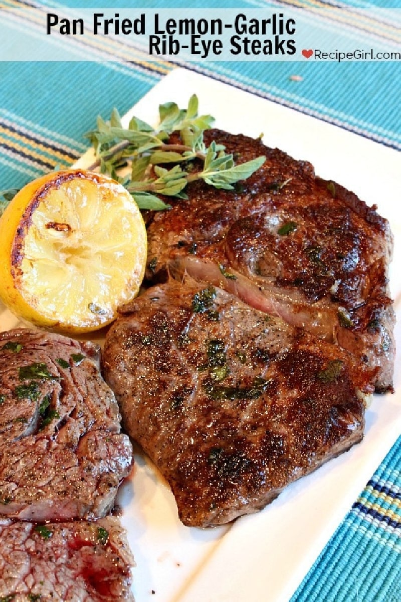 pan fried lemon-garlic rib-eye steaks on a white plate
