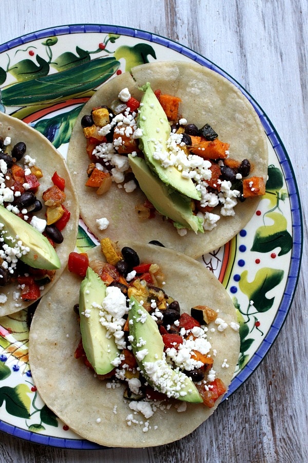 three finished Roasted Vegetable and Black Bean Tacos on a colorful plate