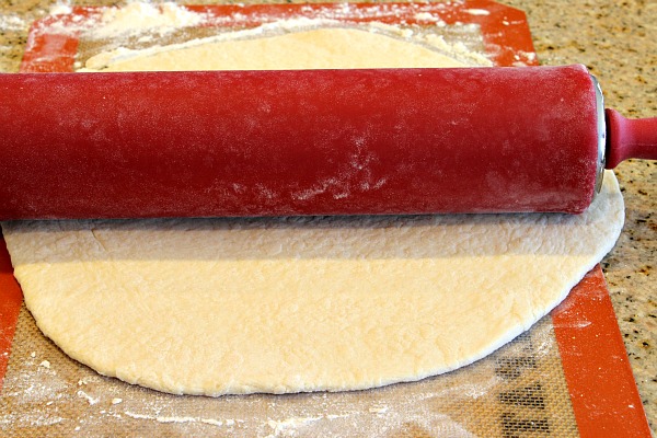 red rolling pin rolling out pizza crust