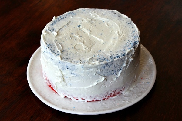 white frosting on a red white and blue layer cake on a white plate