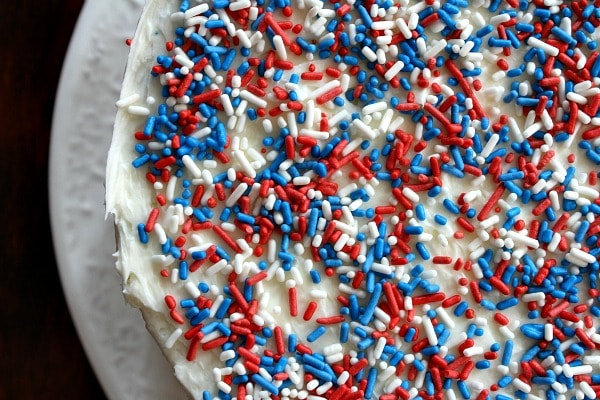 overhead shot of the red white and blue sprinkles on top of a cake on a white plate