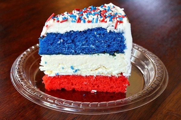 slice of red, white and blue cheesecake cake on a plastic plate on a wood surface