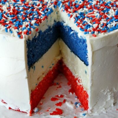 red, white and blue cheesecake cake sliced into to see the inside- displayed on a white plate