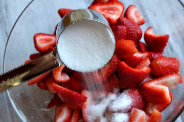 Pouring sugar onto chopped strawberries