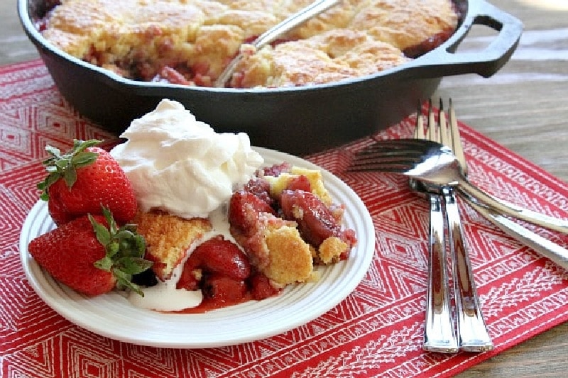 serving of strawberry shortcake skillet cobbler on white plate with whipped cream