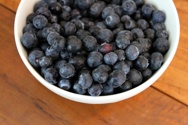 Blueberries in a white dish sitting on a wooden surface